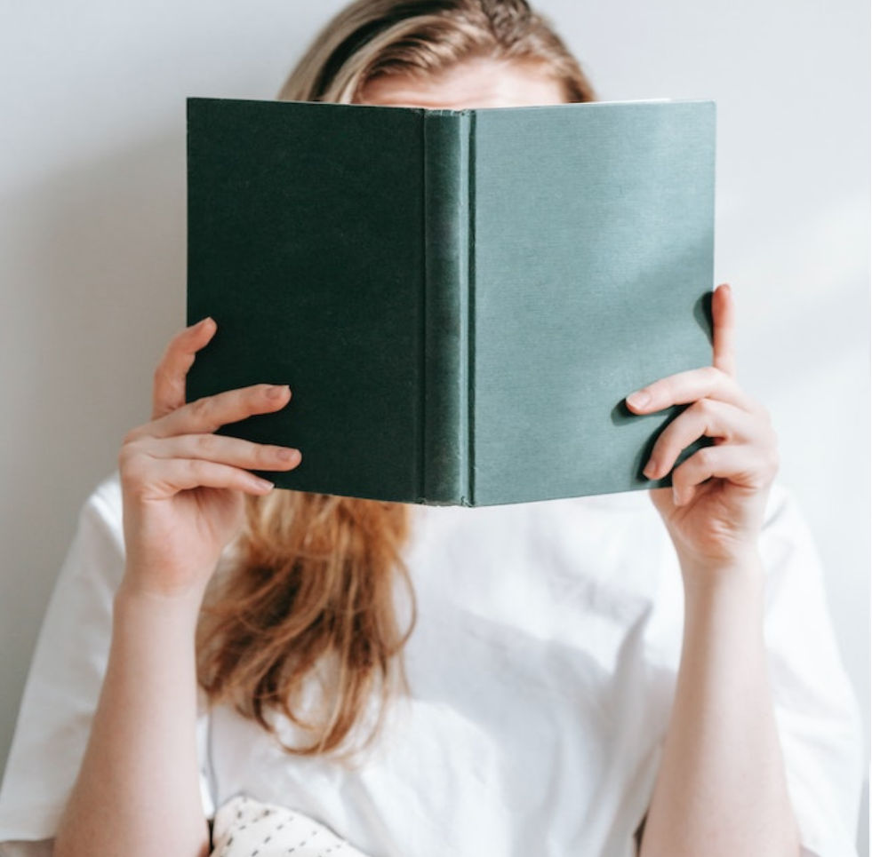 Student reading a book wearing a white t-shirt